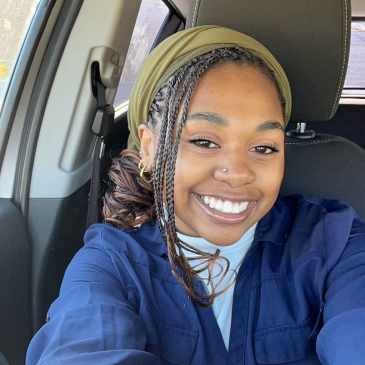  a smiling selfie of CURL Fellowship winner Ally Karabu, taken in a car. She has braided hair and a blue jacket, and her smile is bright and cheery!